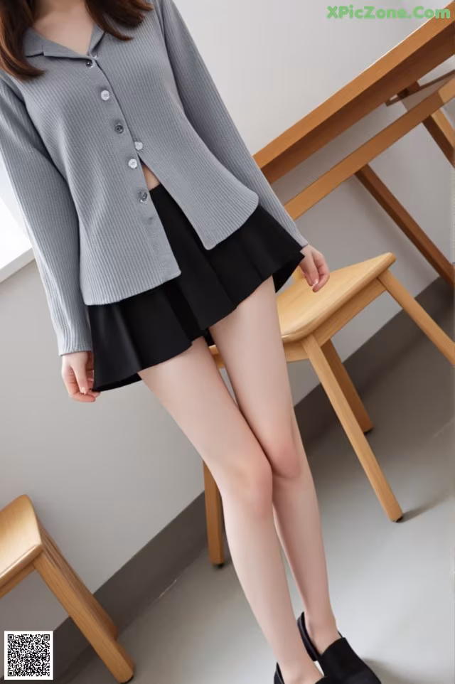 a woman wearing a gray sweater and black skirt