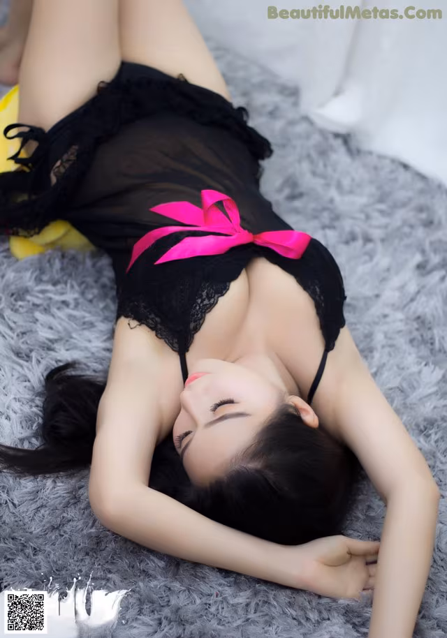 A woman in a black lingerie laying on a gray rug.