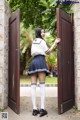 A woman in a school uniform standing in front of a door.