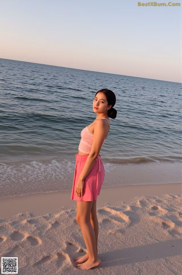 A woman standing on a beach next to the ocean.
