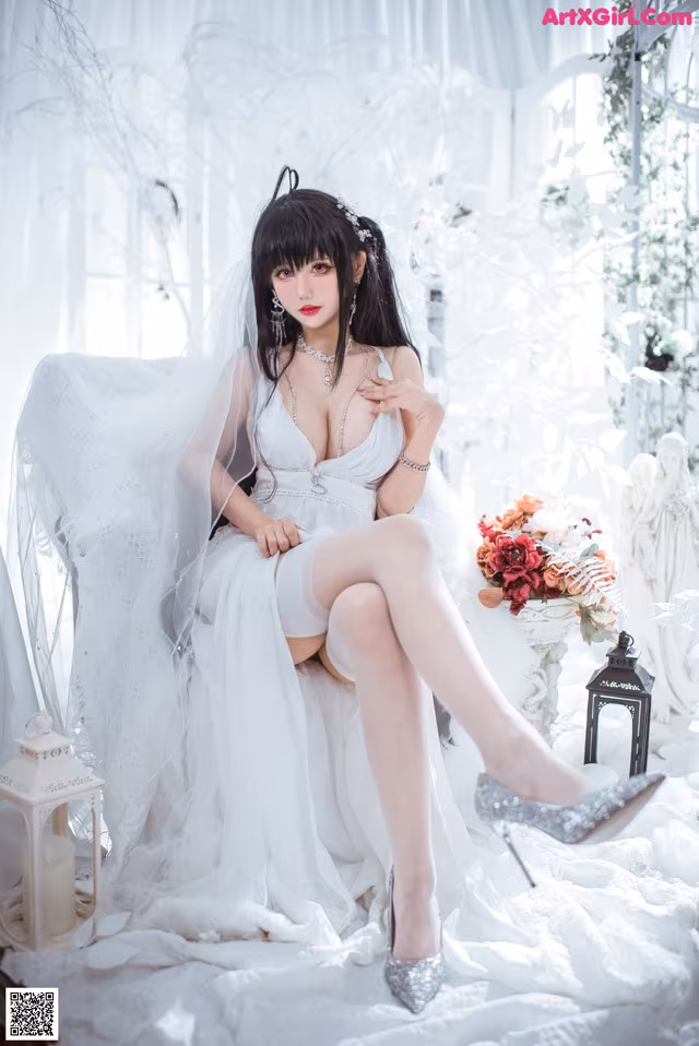 A woman in a wedding dress sitting on a bed.