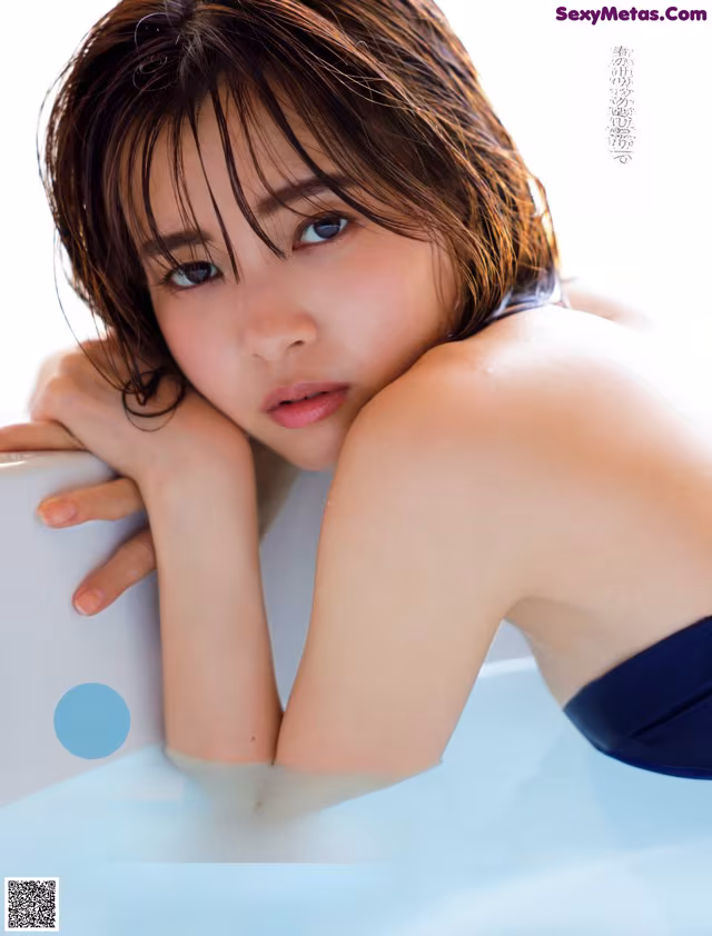 A woman in a blue bikini sitting in a bathtub.