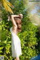 A woman in a white dress standing next to a pool.