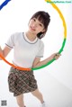 A young woman holding a hula hoop in her hands.