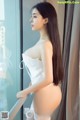 A woman in a white lingerie leaning against a window.