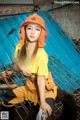 A woman wearing an orange hard hat sitting on a tire.