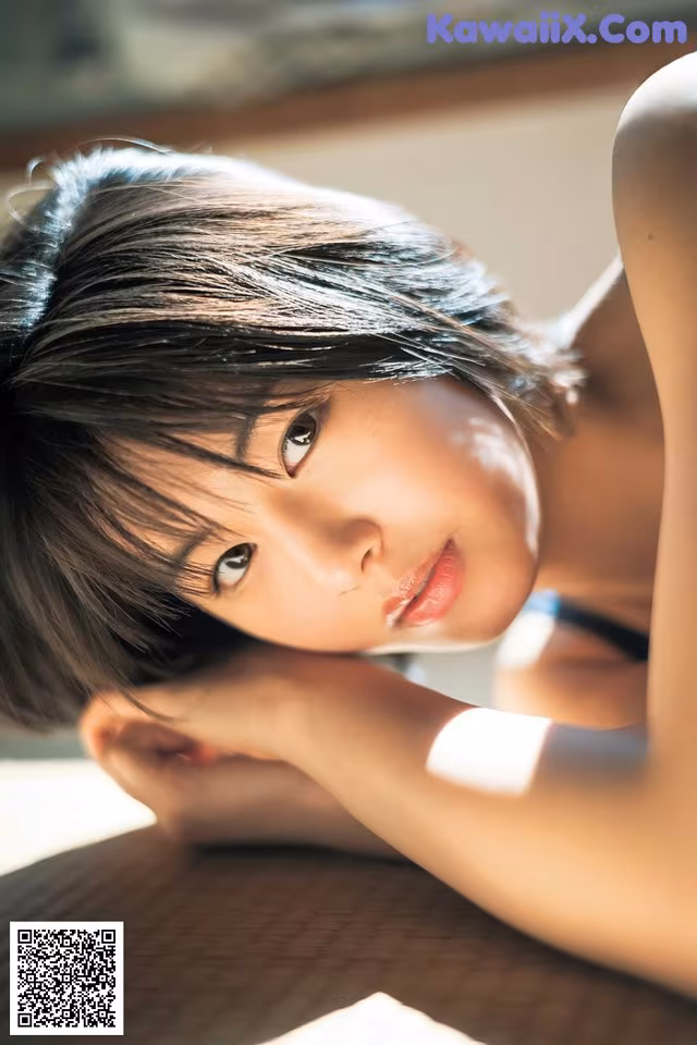 A woman laying on top of a bed next to a window.