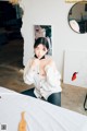 A woman sitting on top of a bed next to a mirror.