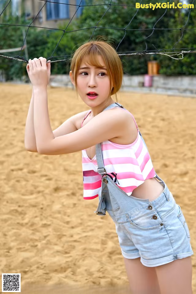 A young woman in a pink and white striped top and denim shorts.