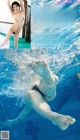 A naked woman in a swimming pool with her feet in the water.