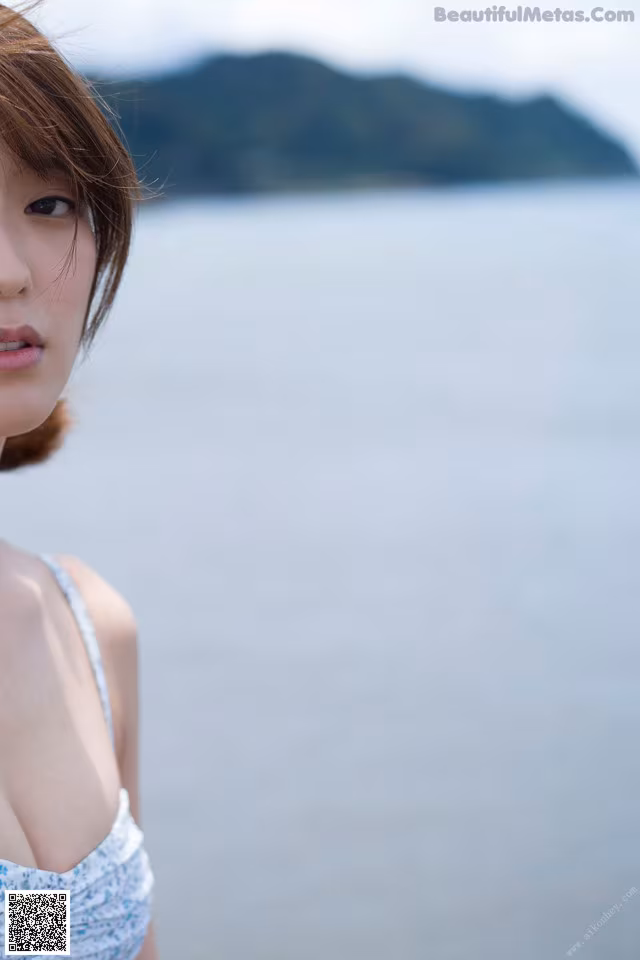 A woman standing in front of a body of water.