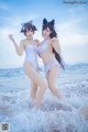 Two women in white bathing suits standing in the ocean.