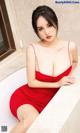 A woman in a red dress sitting in a bathtub.