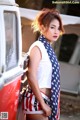 A woman standing next to a red and white van.