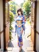 A woman in a blue kimono standing in front of a door.